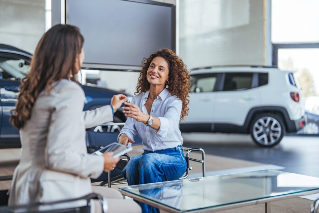 Consulente consegna le chiavi dell'auto a un cliente in concessionaria